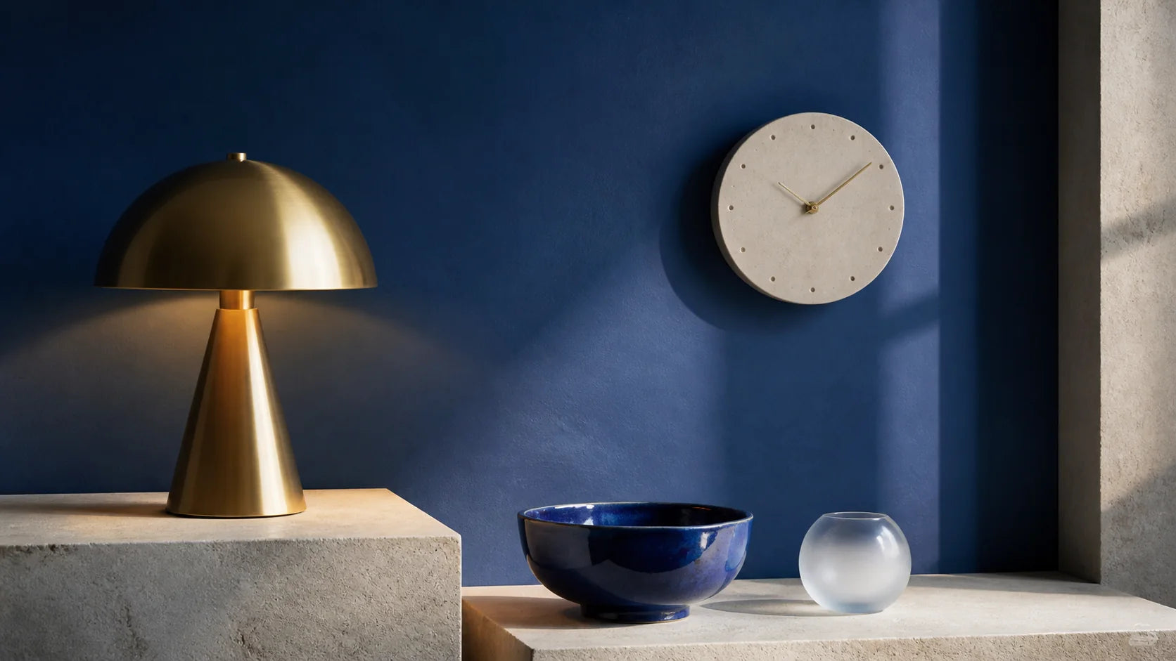 NORDENLY brass table lamp, wall clock and ceramic objects against a cobalt wall